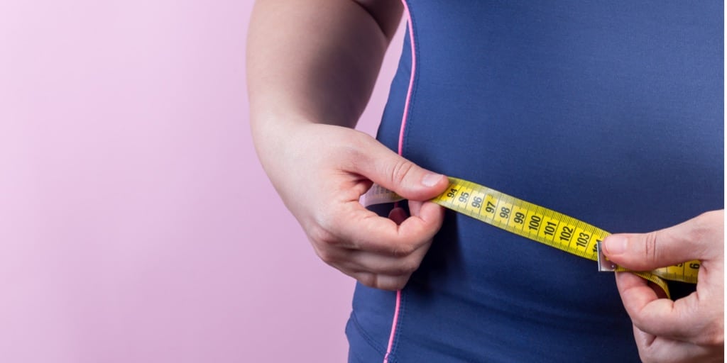 Person måler talje med målebånd (alternativ til BMI-beregner)