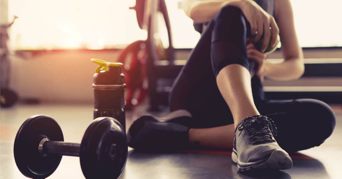 Hvor meget protein om dagen: Kvinde der sidder på gulv med håndvægte foran sig